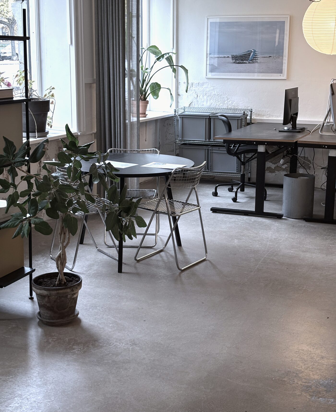 Rundt bord med stole foran vinduet, planter og et billede af en båd på væggen